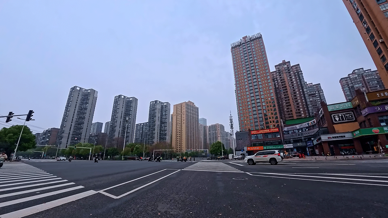 Wide city intersection beneath soft overcast skies during a calm electric scooter ride